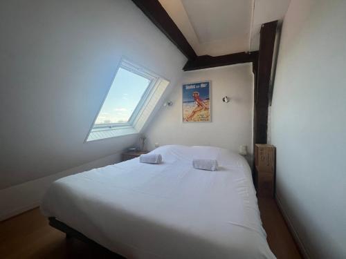 a bedroom with a large white bed with a window at So British ! Appart atypique et sa petite terrasse in Poitiers