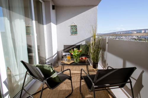 a balcony with two chairs and a table with flowers at Lomená Apartment - Free Garage in Košice