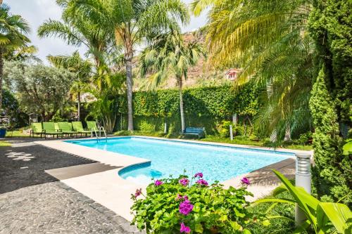 a swimming pool in a yard with palm trees and flowers at Quinta da Tia Briosa by Madeira Sun Travel in Ponta do Sol