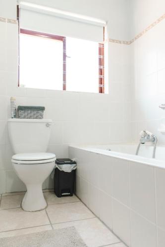 a bathroom with a toilet and a bath tub at Tranquil Private Rooms Hermanus in Hermanus