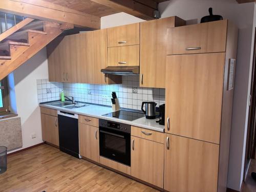 a kitchen with wooden cabinets and a stove top oven at Blockhaus im Bayrischen Wald in Hohenau