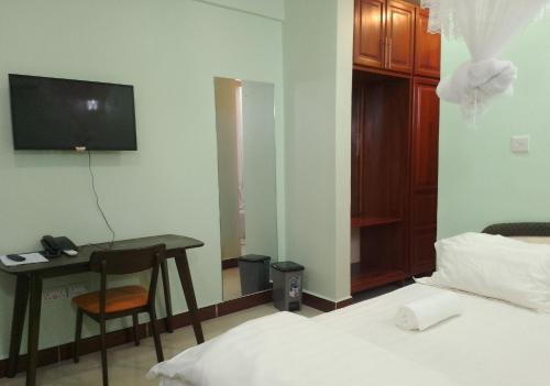 a bedroom with a bed and a desk and a television at Nemart's Hotel in Dar es Salaam