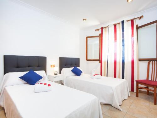 a bedroom with two beds and a red chair at Cas Barber - Villa With Private Pool In Muro in San Lorenzo