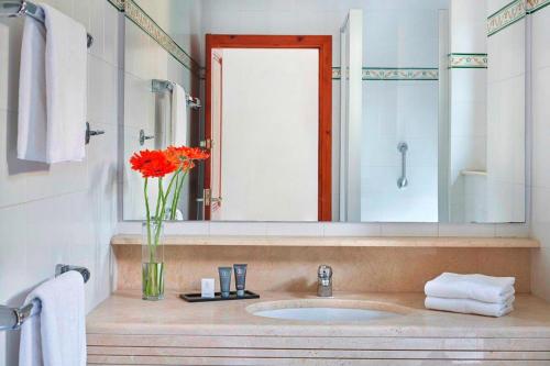 La salle de bains est pourvue d'un lavabo et d'un vase de fleurs orange. dans l'établissement Hapimag Mas Nou holiday resort, Platja d'Aro, à Platja d'Aro