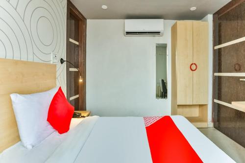 a bedroom with a white bed with red pillows at OYO Happy Inn in New Delhi