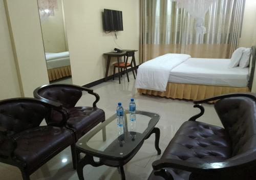 um quarto de hotel com uma cama e duas cadeiras e uma mesa em Nemart's Hotel em Dar es Salaam