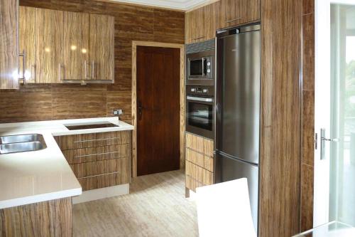 a kitchen with wooden cabinets and a stainless steel refrigerator at holiday home Caserio Lomo Arriba Torre del Sol Vera de Erques in Vera de Erque