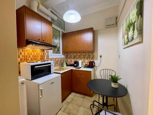 una pequeña cocina con armarios de madera y una mesa pequeña en Athens Spirit Apartment en Athens