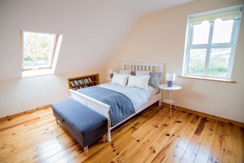 1 dormitorio con 1 cama, 1 mesa y 2 ventanas en *Spacious Irish Cottage*, en Fanore