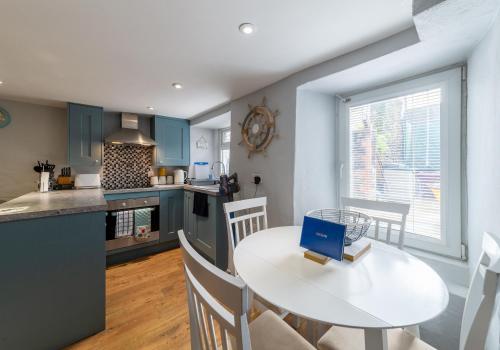 a kitchen and dining room with a white table and chairs at Inviting Traditional Fishermens cottage in the heart of the village, close to the harbour in Mevagissey