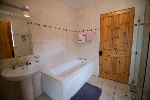y baño con bañera, lavabo y aseo. en *Spacious Irish Cottage*, en Fanore