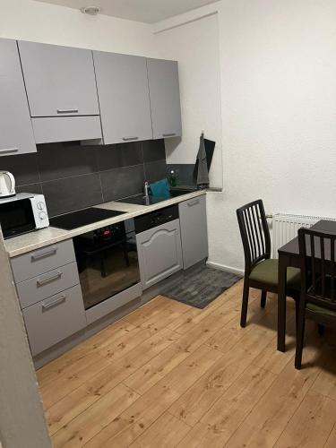 een keuken met witte kasten en een tafel en stoelen bij Appartement Cormondrèche in Neuchâtel