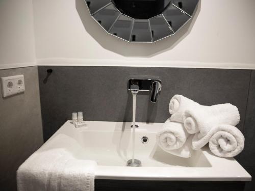 La salle de bains est pourvue d'un lavabo avec un miroir et de serviettes. dans l'établissement Hotel KUMP365, à Paderborn