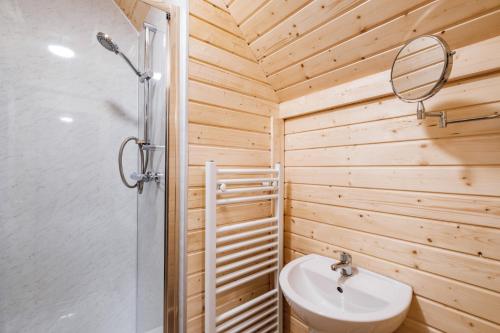 a bathroom with a shower and a sink and a mirror at Cairngorm Bothies in Aboyne
