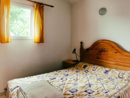 a bedroom with a bed with a wooden headboard and a window at Rustic Mountain Retreat in La Puebla de Roda