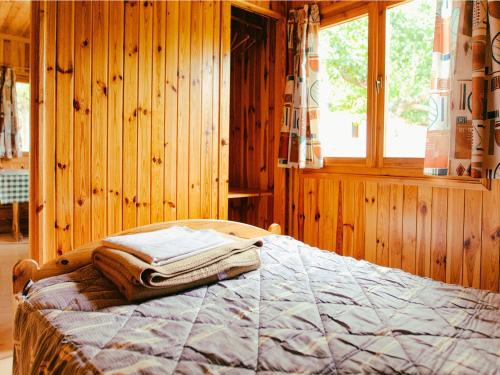 Un dormitorio de madera con una cama con toallas. en Holiday home Vakantiepark Isábena 6, en La Puebla de Roda