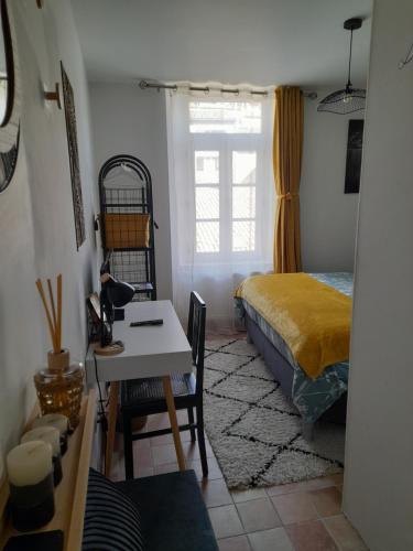 una camera con letto, scrivania e tavolo di Les MIRABELLES chambres d'hôtes a Sisteron