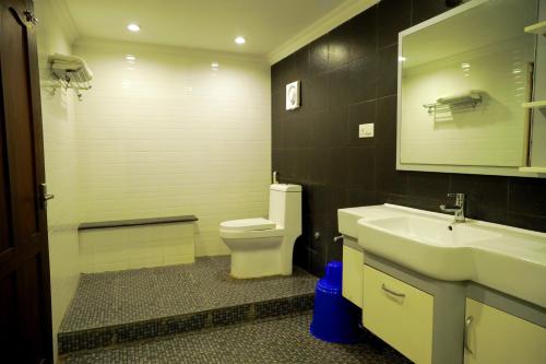 a bathroom with a sink and a toilet and a mirror at GRANDE IVORY INN in Kalpetta