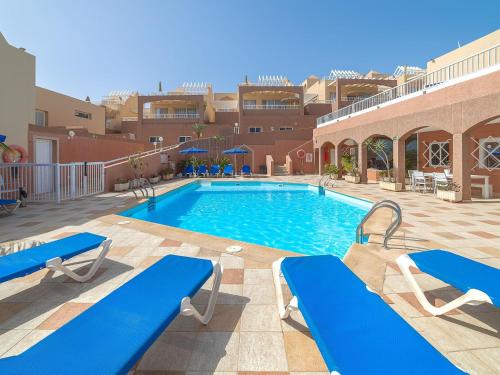 a swimming pool with blue chairs and a building at Vacation Rentals Villas Monte Solana Jand a in Morro del Jable
