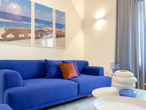 a living room with a blue couch and a table at Stylish Villa with Bomb Shelter Close to Shore in Caesarea