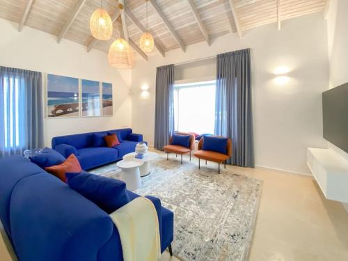 a living room with a blue couch and chairs at Stylish Villa with Bomb Shelter Close to Shore in Caesarea