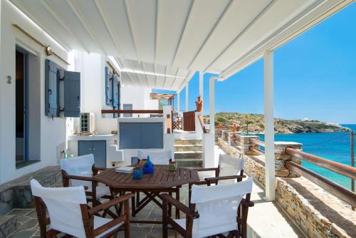a wooden table and chairs on a balcony with the ocean at Ammos 2 - Seafront maisonette, Glyfo beach, Sifnos in Chrisopigi