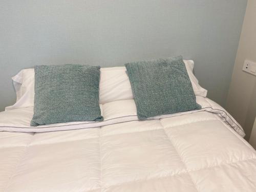 two green pillows sitting on top of a bed at Apartamentos TARELA Porriño in Porriño
