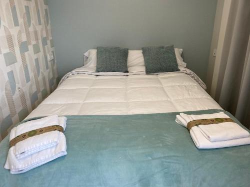 a bed with white sheets and towels on it at Apartamentos TARELA Porriño in Porriño