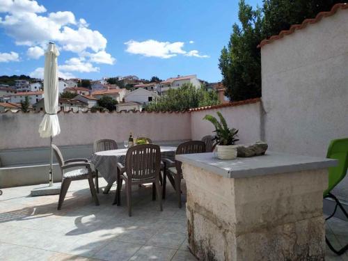a patio with a table and chairs and an umbrella at Greta in Vrbnik