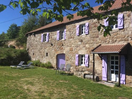 Cros-de-GéorandにあるCharming Farmhouse in Cros de G orand with Swimming Poolの紫色のドアと椅子が外に並ぶ石造りの建物