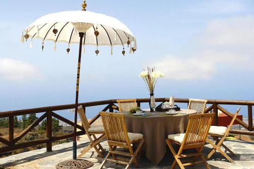 een tafel met stoelen en een parasol op een balkon bij holiday home Caserio Lomo Arriba Casa Tia Benigna Vera de Erques in Vera de Erque