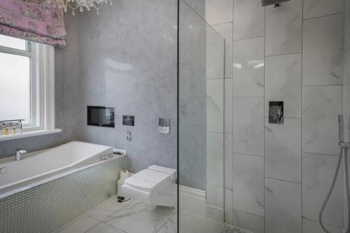 Un baño con bañera, inodoro y ducha. en Mode Breck Apartments, en Poulton le Fylde