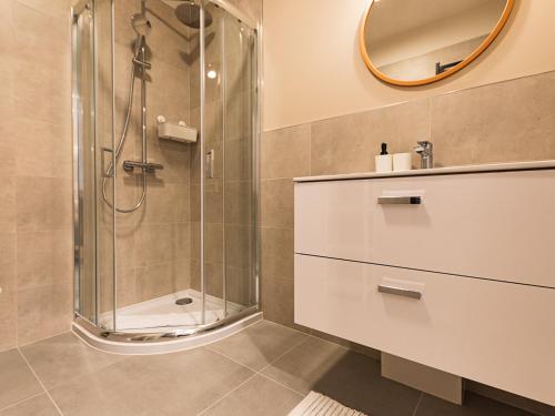 a bathroom with a shower and a sink and a mirror at VacationClub - Apartamenty Zakopiańskie Apartament 51 in Zakopane
