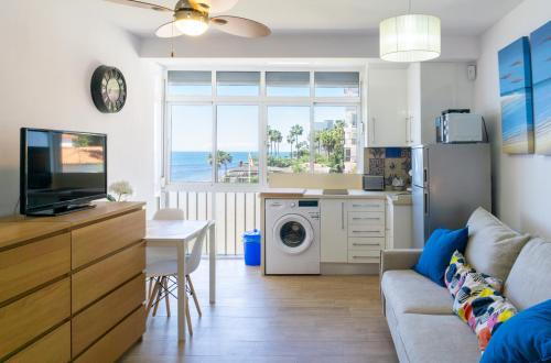a living room with a couch and a kitchen with a washing machine at Mijas Sea Views Apartment in Mijas