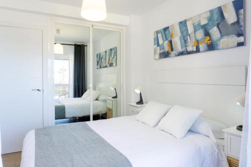a white bedroom with a bed and a mirror at Mijas Sea Views Apartment in Mijas Costa