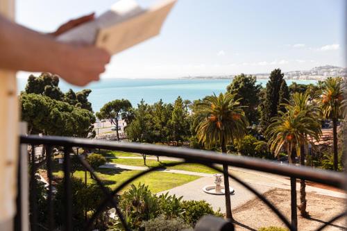 una persona parada en un balcón con vistas al océano en Albert 1er en Niza