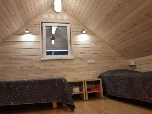 een kamer met 2 bedden en een raam op een zolder bij Liedaga namiņš in Mērsrags