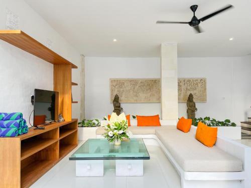 a living room with a white couch and orange pillows at Apple Villas & Apartments in Kerobokan
