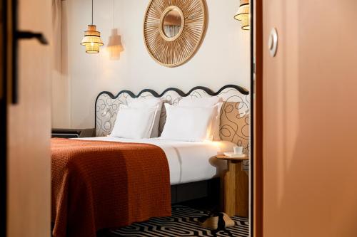 a bedroom with a bed with white pillows and a mirror at Albert 1er in Nice