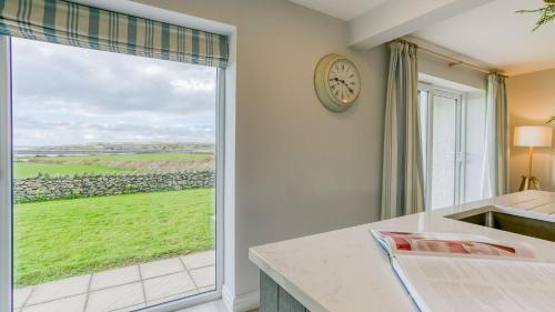 a kitchen with a large window and a clock at Penrhyn Isaf Dau in Aberffraw
