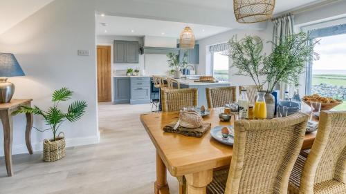 a kitchen and dining room with a wooden table and chairs at Penrhyn Isaf Dau in Aberffraw