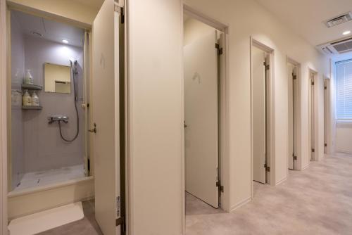 a hallway with a walk in shower and a row of doors at シティキャビンすすきの in Sapporo