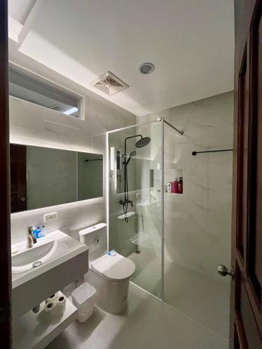 a bathroom with a shower and a toilet and a sink at Minnie's Guest House in Taytay