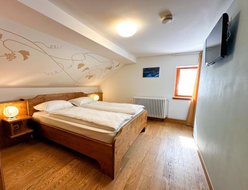 um quarto com uma cama e uma televisão de ecrã plano em Locanda Orelli em Bedretto