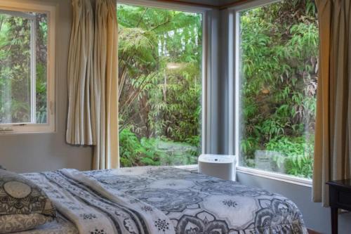 a bedroom with a bed and a large window at Volcano Inn Bed n Breakfast in Volcano