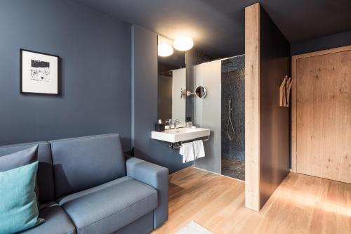 ein Wohnzimmer mit einem blauen Sofa und einem Waschbecken in der Unterkunft Hotel Lamm in Kastelruth
