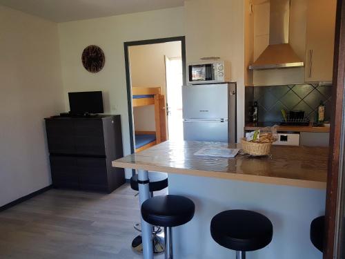 La cuisine est équipée d'un comptoir avec tabourets et d'un réfrigérateur. dans l'établissement Appartement confortable à Nice, 25 m² avec piscine partagée, à Nice