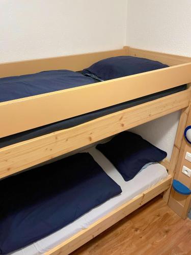 Elle comprend un lit superposé en bois avec des oreillers bleus. dans l'établissement Appartement confortable à Nice, 25 m² avec piscine partagée, à Nice