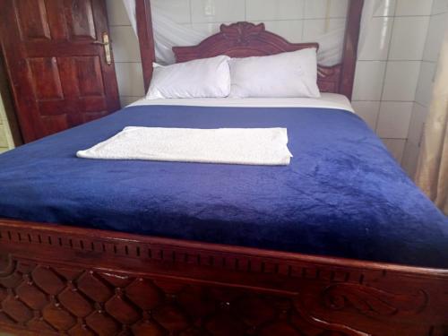 a bed with a blue blanket and a white towel on it at Oasis Hotel and Guest House. Voi in Voi