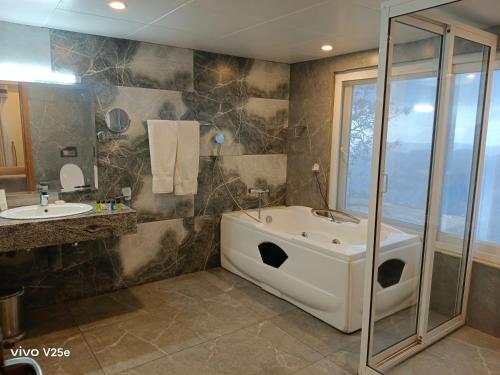 a bathroom with a bath tub and a sink at Falettis Grand Hotel Murree in Murree